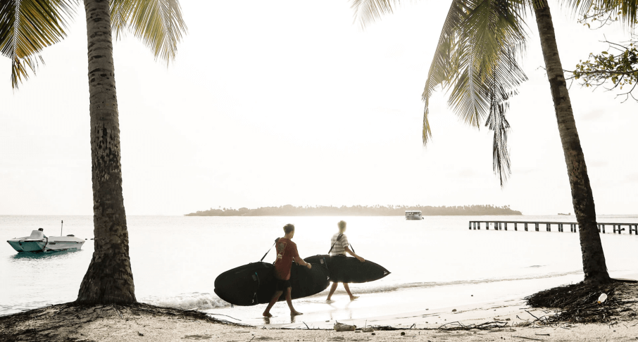 zwei Surfer mit Boardbags am Strand